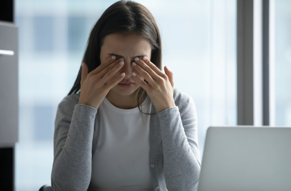 A woman rubbing her eyes after working in front of a laptop monitor for an extended amount of time.