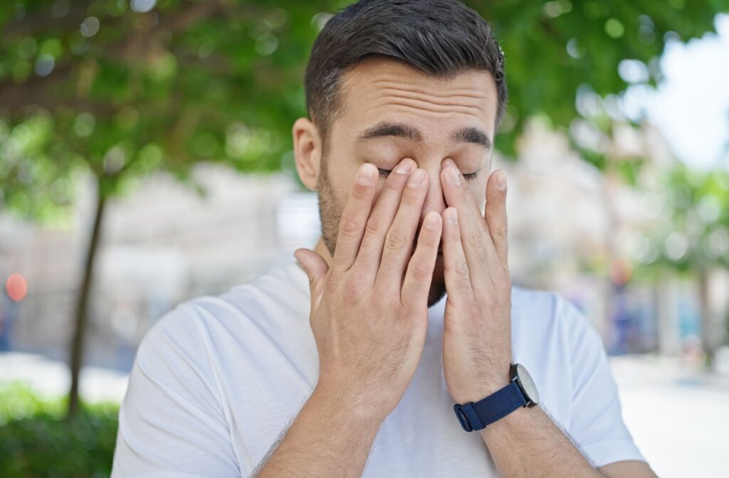 A man with his hands on his eyes as he experiences the symptoms of dry eye disease, which can be treated with low-level light therapy