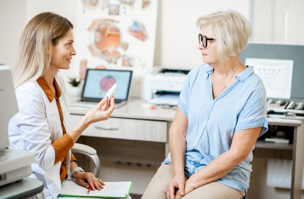 An optometrist holding up a bottle of eye drops while explaining how to safely use them after an eye exam.